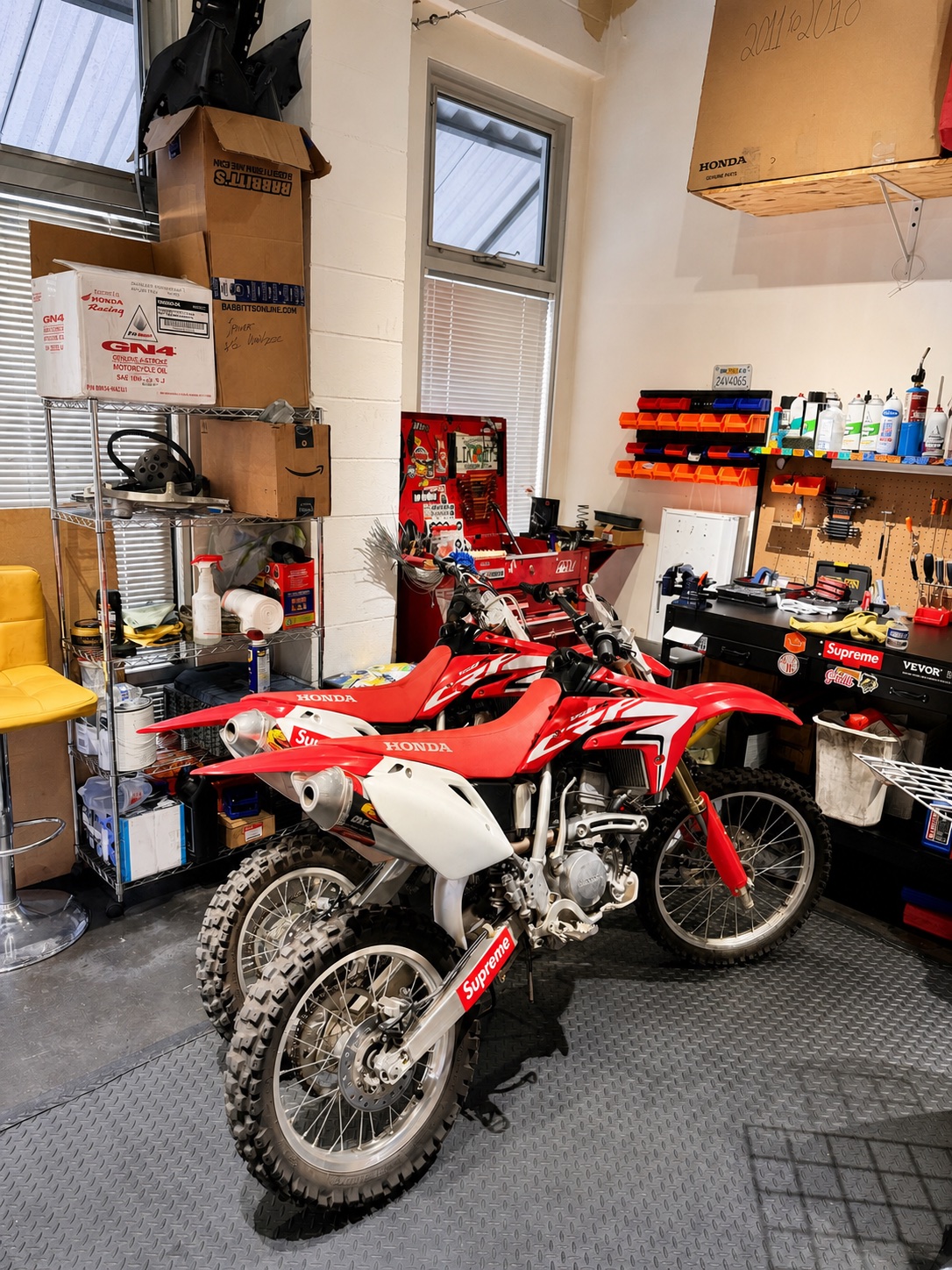 Two red Honda off-road motorcycles inside the Real Facts workshop